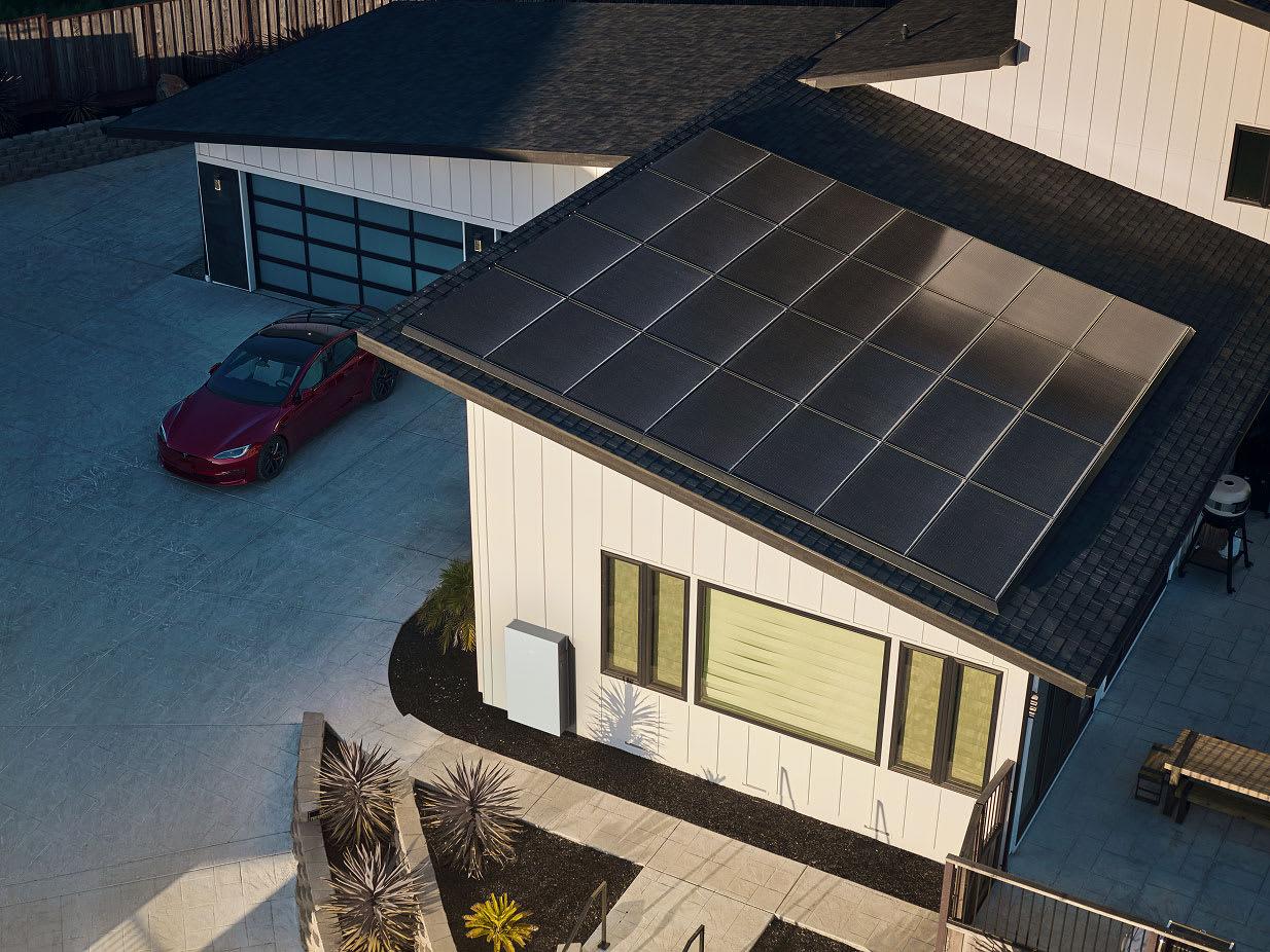Aerial view of a home with solar panels and Tesla Powerwall installed on the side